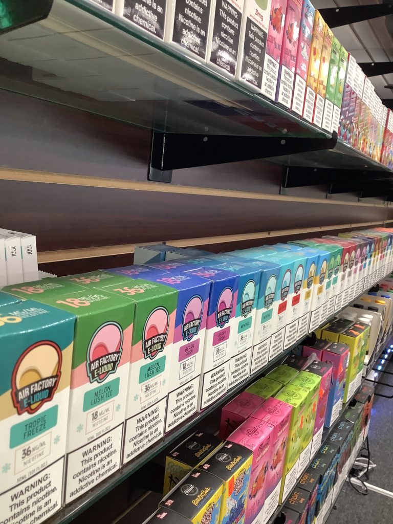Shelves stocked with various colorful vape juice boxes arranged in rows inside a store.